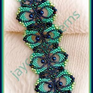 Peut inclure: Un bracelet en perles vert et bleu avec un fermoir doré. Le bracelet est réalisé avec de petites perles de rocaille et présente un design délicat et complexe. Le bracelet s'appelle "La Concha Bracelet".