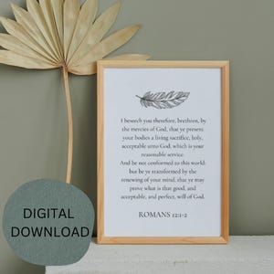 May include: A framed print with a light wood frame. The print features text from Romans 12:1-2 and a feather illustration. The words "DIGITAL DOWNLOAD" are in a circle in the lower left corner. A dried palm leaf is in the background.