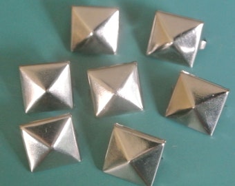 May include: Seven silver pyramid-shaped studs with a square base. The studs have a shiny, metallic finish.