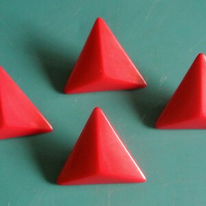 Pode incluir: Quatro botões de plástico vermelho em forma de pirâmide.