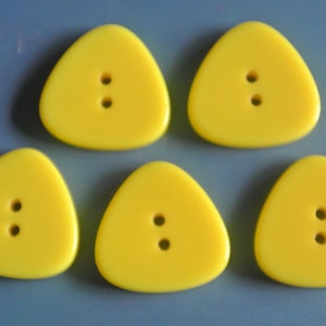 May include: Five yellow triangle-shaped buttons with two holes each.