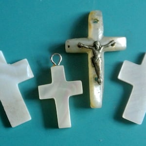 May include: Four white mother of pearl crosses with a silver crucifix on one of the crosses.