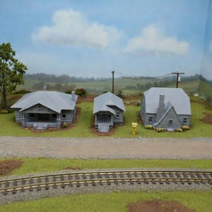 May include: A set of three ceramic mugs with a speckled, matte finish. The mugs are in shades of cream, light gray, and dark gray. Each mug has a simple, minimalist design and a rounded handle.