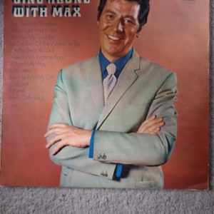 May include: Vintage vinyl record album cover titled "Sing Along With Max." The cover features a smiling man in a light green suit, blue shirt, and patterned tie. The album's tracklist is visible on the left side.