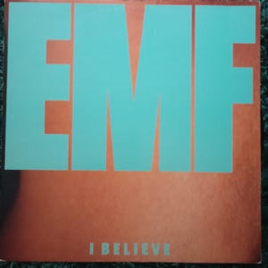 Puede incluir: Una portada de álbum de vinilo con la palabra "EMF" en letras grandes de color turquesa. Debajo, las palabras "I BELIEVE" están impresas en turquesa. El fondo es de color marrón rojizo.