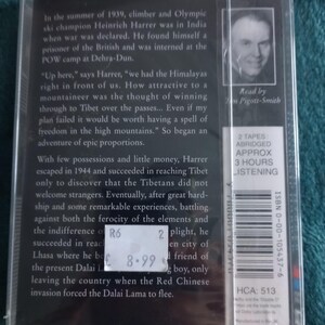 Op de afbeelding: Een verpakte audiocassette met tekst die de reis van een bergbeklimmer naar Tibet beschrijft. De hoes heeft een zwart-wit portret en een prijskaartje. De tekst is in het Engels.