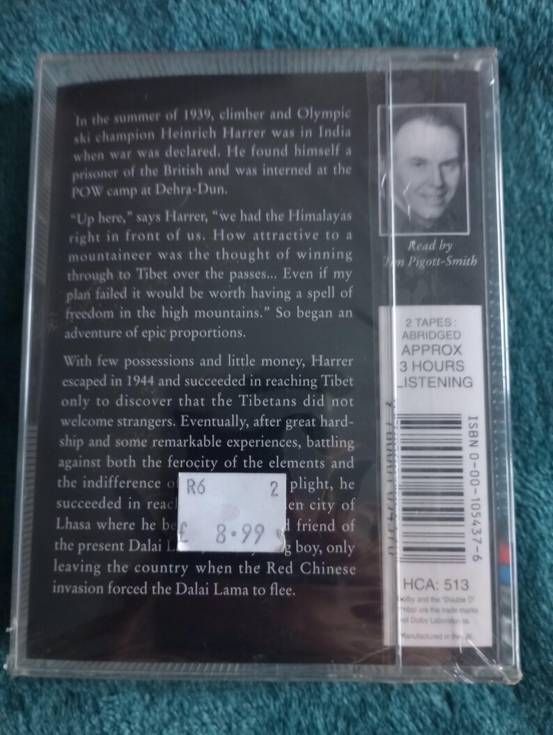 Op de afbeelding: Een verpakte audiocassette met tekst die de reis van een bergbeklimmer naar Tibet beschrijft. De hoes heeft een zwart-wit portret en een prijskaartje. De tekst is in het Engels.