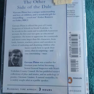 Op de afbeelding: Een Penguin Audiobooks cassette van "The Other Side of the Dale" van Gervase Phinn. De cover bevat tekst en een foto van de auteur. De looptijd is ongeveer 3 uur. De cassette zit in een doorzichtige plastic hoes.