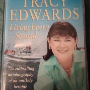 Puede incluir: Una portada de libro con el título "TRACY EDWARDS" en letras doradas sobre un fondo azul. El libro se titula "Living Every Second" y presenta una foto de una mujer sonriente. La portada también incluye el texto "The enthralling autobiography of an unlikely heroine."