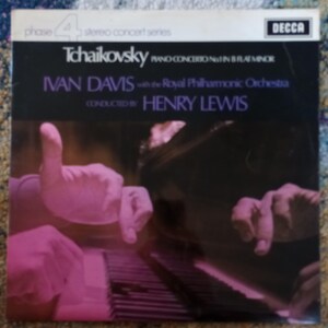 May include: A vintage vinyl record album cover featuring the text "Tchaikovsky Piano Concerto No. 1 in B flat minor" with "Ivan Davis" and "Henry Lewis" as the artist names. The cover art shows a pianist's hands over a piano keyboard, with a pinkish hue.