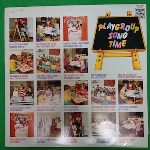 Könnte beinhalten: Ein Vintage-Vinyl-Schallplattencover mit dem Titel "Playgroup Song Time". Das Cover zeigt eine schwarze Tafel mit gelbem Rand und dem Titel in bunten Buchstaben. Es enthält verschiedene Illustrationen von Kindern und Songtiteln.