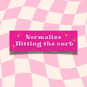 May include: Pink and white checkered background with a pink banner that says "Normalize hitting the curb" in a retro font with gold stars.