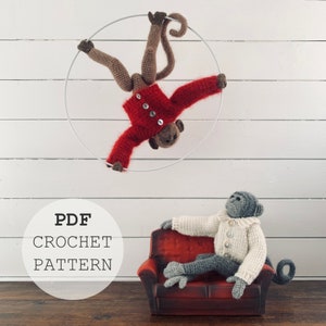 Pode incluir: Brinquedos de macaco de crochê. Um pendura-se num arco prateado, usando um suéter vermelho. O outro está sentado num sofá vermelho em miniatura, usando um suéter branco. O texto "PDF CROCHET PATTERN" está num círculo.