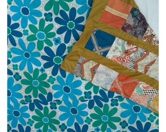May include: A patchwork quilt with a floral pattern on one side and a patchwork of different fabrics on the other side. The floral side features blue and green flowers on a white background.