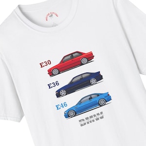 May include: White t-shirt featuring illustrations of three BMW cars: a red E30, a blue E36, and a light blue E46. The shirt includes the text "BMW Classic Coupe Sport" and the Motor Custom logo.