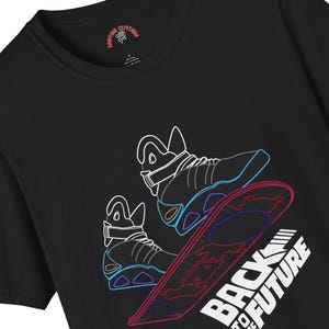 May include: Black t-shirt with a neon outline graphic of a pair of self-lacing shoes and a hoverboard. The text "Back to the Future" is printed below the graphic.