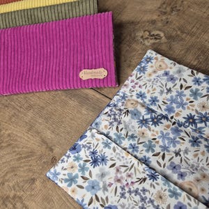 Peut inclure: Divers éléments en tissu, dont du velours côtelé et des motifs floraux. Les pièces en velours côtelé sont dans les tons orange, jaune, vert et magenta. Le tissu floral présente des fleurs bleues et violettes. Une petite étiquette indique "Handmade".