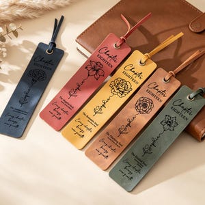 Op de afbeelding: Vijf rechthoekige leren boekenleggers in marineblauw, rood, geel, beige en groen, elk voorzien van een metalen oogje met een bijpassend leren koordje. Elke boekenlegger is gegraveerd met de tekst Chapter Eighteen, de naam Sophia en een bloem.