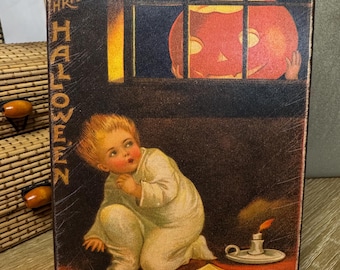 May include: Vintage Halloween-themed rectangular wooden plaque. The artwork depicts a child in a white outfit, a jack-o'-lantern, and a lit candle. The text "THE HALLOWEEN" and "YE GHOST" are visible. The top edge has a decorative lace trim.
