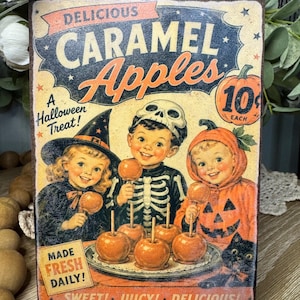 May include: Vintage-style Halloween sign featuring the words "Delicious Caramel Apples." The sign depicts three children in costumes holding caramel apples. Text includes "A Halloween Treat!" and "Made Fresh Daily!"