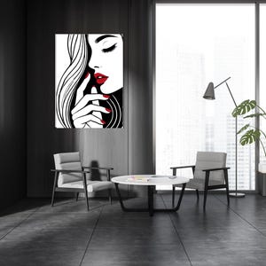 以下が含まれることがあります： 赤色の唇と爪をした女性の顔の白黒の線画プリント。プリントは額装され、モダンなインテリアの壁にかけられています。