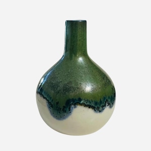 May include: A handcrafted ceramic vase with a rounded body and a narrow neck. The vase features a gradient of colors, with a green top, a dark blue and black midsection, and a cream-colored base. The glossy finish enhances the colors.