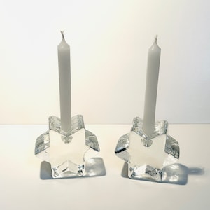 May include: Two clear glass star-shaped candle holders with white candles.