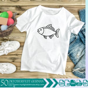 以下が含まれることがあります： 白いTシャツに、黒い魚の輪郭が前面に描かれています。Tシャツは、カラフルなイースターエッグの入ったバスケットと青いジーンズと一緒に、木製の表面に置かれています。