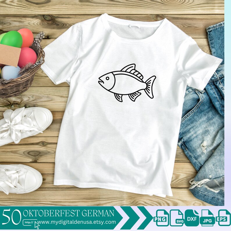 以下が含まれることがあります： 白いTシャツに、黒い魚の輪郭が前面に描かれています。Tシャツは、カラフルなイースターエッグの入ったバスケットと青いジーンズと一緒に、木製の表面に置かれています。