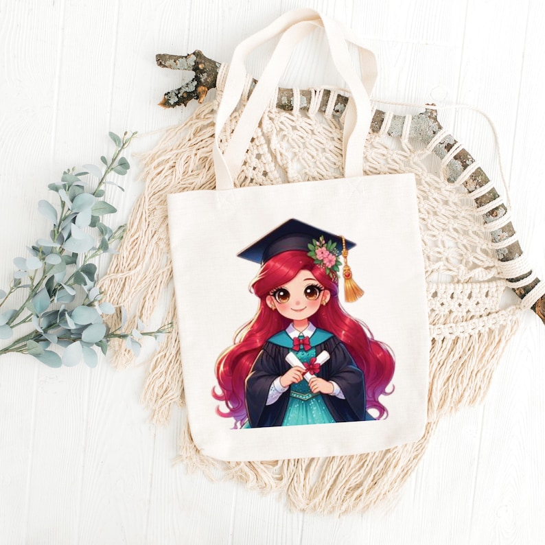 May include: Cream-colored tote bag featuring a cartoon illustration of a graduate with long red hair, wearing a graduation cap and gown, holding a diploma. The bag has cream-colored handles and is made of a sturdy fabric.