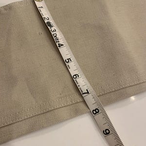 May include: Close-up of a beige fabric with a measuring tape showing a width of approximately 6 inches. The tape is marked with inch increments and the text "MADE IN CHINA".