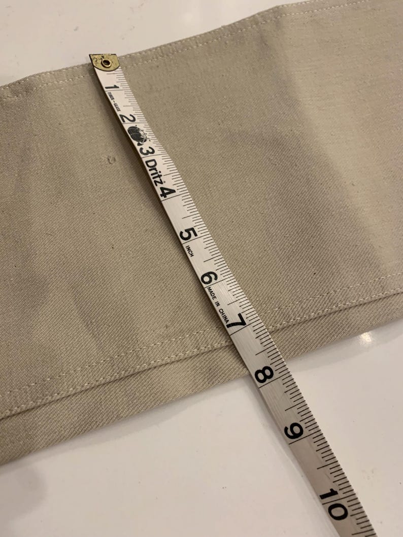 May include: Close-up of a beige fabric with a measuring tape showing a width of approximately 6 inches. The tape is marked with inch increments and the text "MADE IN CHINA".