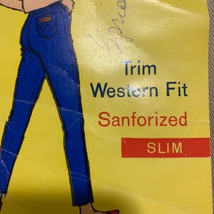 May include: A yellow paper with an illustration of blue jeans and the words "Trim Western Fit Sanforized SLIM." The text "MADE IN U.S.A." is at the top. A handwritten signature is visible.