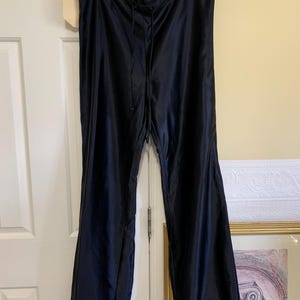 May include: Black nylon trousers with a drawstring waist and elasticated cuffs. The trousers are hanging on a hanger.