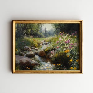 May include: A framed landscape painting depicts a serene stream flowing through a lush, flower-filled meadow. The artwork features a gold-colored frame and showcases vibrant wildflowers in pink, yellow, and white, with a backdrop of green trees and foliage.