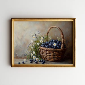 May include: A still-life painting depicts a woven basket overflowing with ripe blueberries. White daisies and lavender sprigs spill from the basket, adding a touch of freshness. The painting is framed in a gold-colored frame.