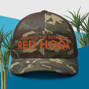 May include: A brown and green camouflage trucker hat with the text "all bars, no activities RED HOOK" embroidered in orange.