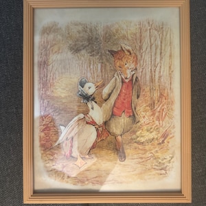 May include: A framed watercolor print featuring a fox and a goose in a forest setting. The fox, dressed in a coat and vest, appears surprised, while the goose wears a bonnet and scarf. The artwork has a vintage, storybook aesthetic.