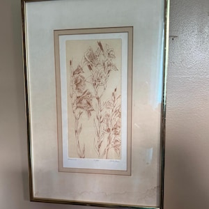 May include: Framed botanical print featuring a detailed illustration of gladiolus flowers in shades of brown and beige. The artwork is encased in a gold-toned frame with a cream-colored matting, creating a classic and elegant aesthetic.