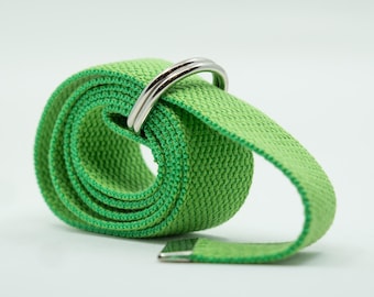 May include: A bright green canvas belt with a silver-colored metal buckle and loop. The belt is rolled up, showcasing its woven texture. The buckle is a simple, double-loop design.