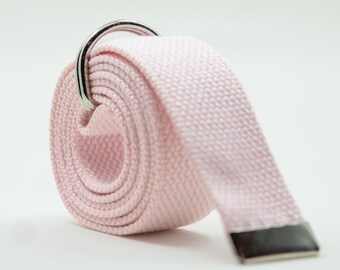 May include: A rolled-up, light pink canvas belt with a silver-colored D-ring buckle. The belt's end has a silver-colored metal tip. The belt is made of a woven fabric.