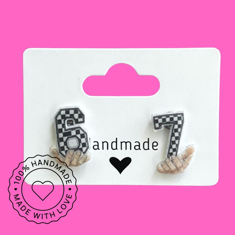 May include: Earrings featuring the numbers 6 and 7 in a black and white checkered pattern, held by hands. The card reads "handmade" with a heart symbol. A circular sticker says "100% handmade with love."