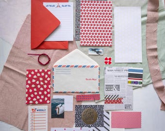 May include: A collection of stationery items, including a red envelope with matching paper, patterned cards, and an airmail envelope. Various decorative elements like washi tape, stickers, and a small bird illustration are also present. The color palette includes red, white, and blue.