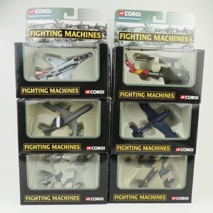May include: A collection of Corgi Fighting Machines model aircraft in their original packaging. The models include various military aircraft, such as jets and helicopters, with detailed paint schemes and markings. The packaging features the "Fighting Machines" logo and the Corgi brand.