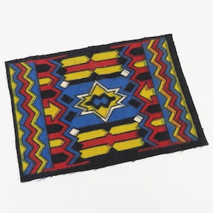 May include: A small, rectangular rug with a geometric design. The rug features a black border and a central pattern in blue, yellow, and red. The design includes zigzags, arrows, and star-like shapes.