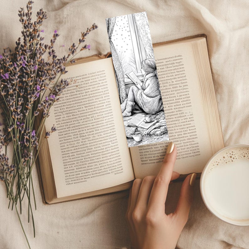 May include: A black and white bookmark featuring a person reading by a window, placed in an open book. The image includes a cup of coffee, lavender, and a hand with a gold painted nail.
