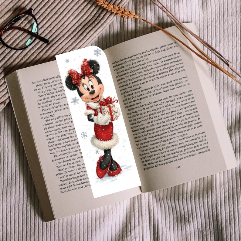 Peut inclure: Un marque-page vertical illustr&eacute; d'une souris de dessin anim&eacute; portant une robe rouge &agrave; bordure en fourrure blanche, un n&oelig;ud rouge assorti et des chaussures rouges. Elle tient un cadeau, entour&eacute;e de flocons de neige sur fond blanc.
