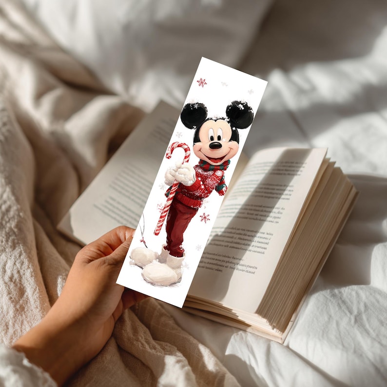 Peut inclure: Un marque-page rectangulaire en papier illustr&eacute; d'une souris de dessin anim&eacute; portant un pull d'hiver &agrave; motifs rouges et blancs, une &eacute;charpe rouge et des bottes blanches. Le personnage tient une canne en sucre ray&eacute;e rouge et blanche.