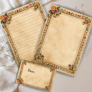 May include: Three pieces of stationery with a vintage floral design. The paper has a cream color with a decorative border of flowers and leaves in shades of blue, orange, and green. One sheet is lined, another is blank, and a smaller card reads "Dear,".