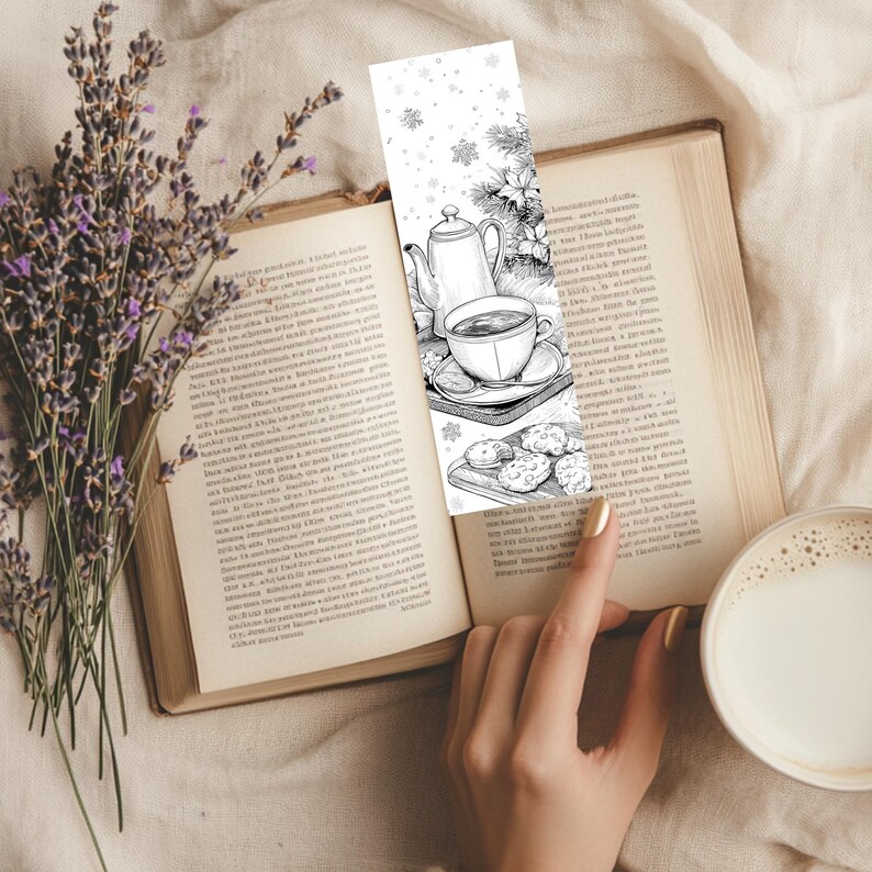 May include: A black and white bookmark featuring a tea set, cookies, and snowflakes, inserted into an open book. A sprig of lavender and a cup of coffee with milk are also visible.